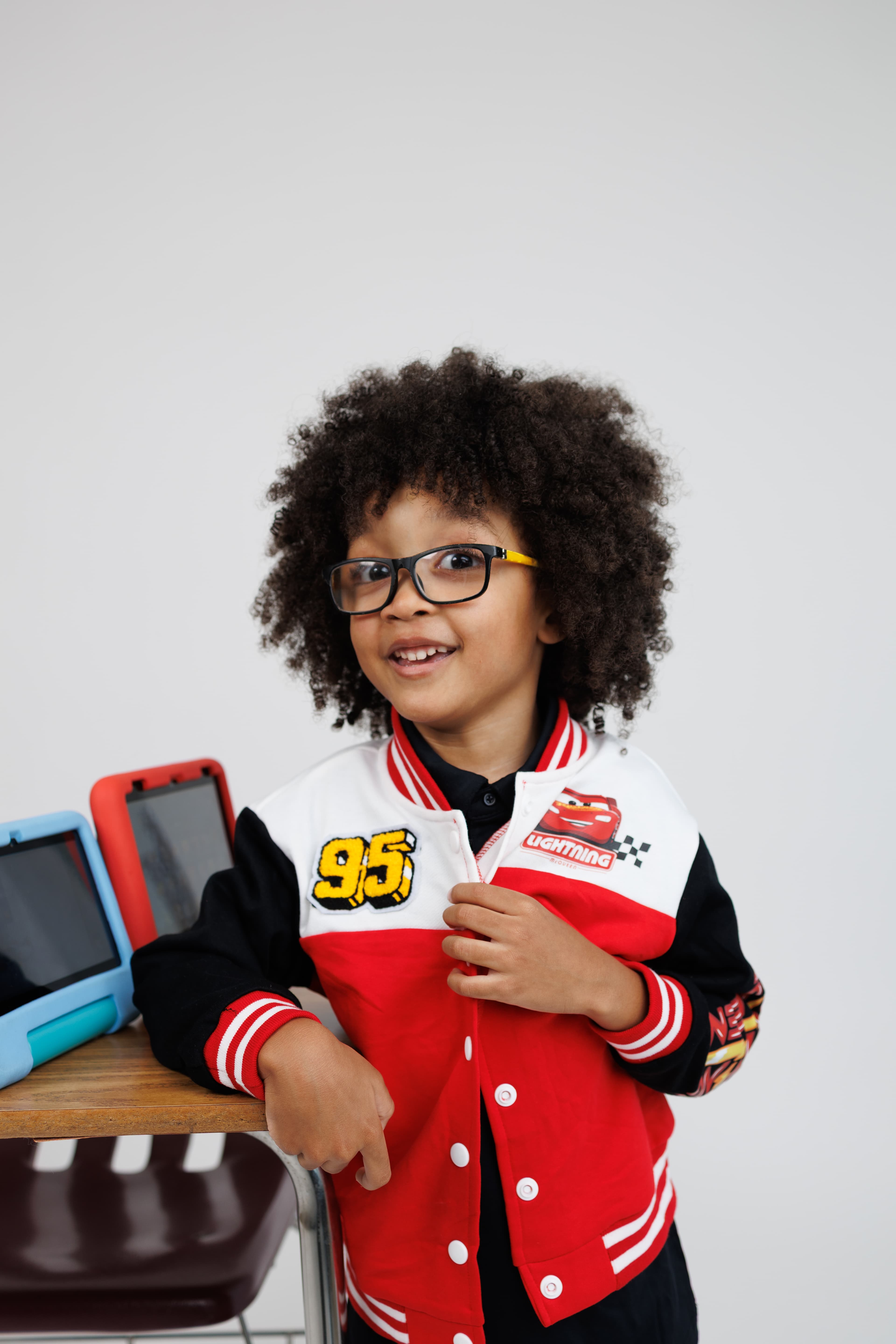 A portrait of the founder's son smiling in glasses and a red jacket.